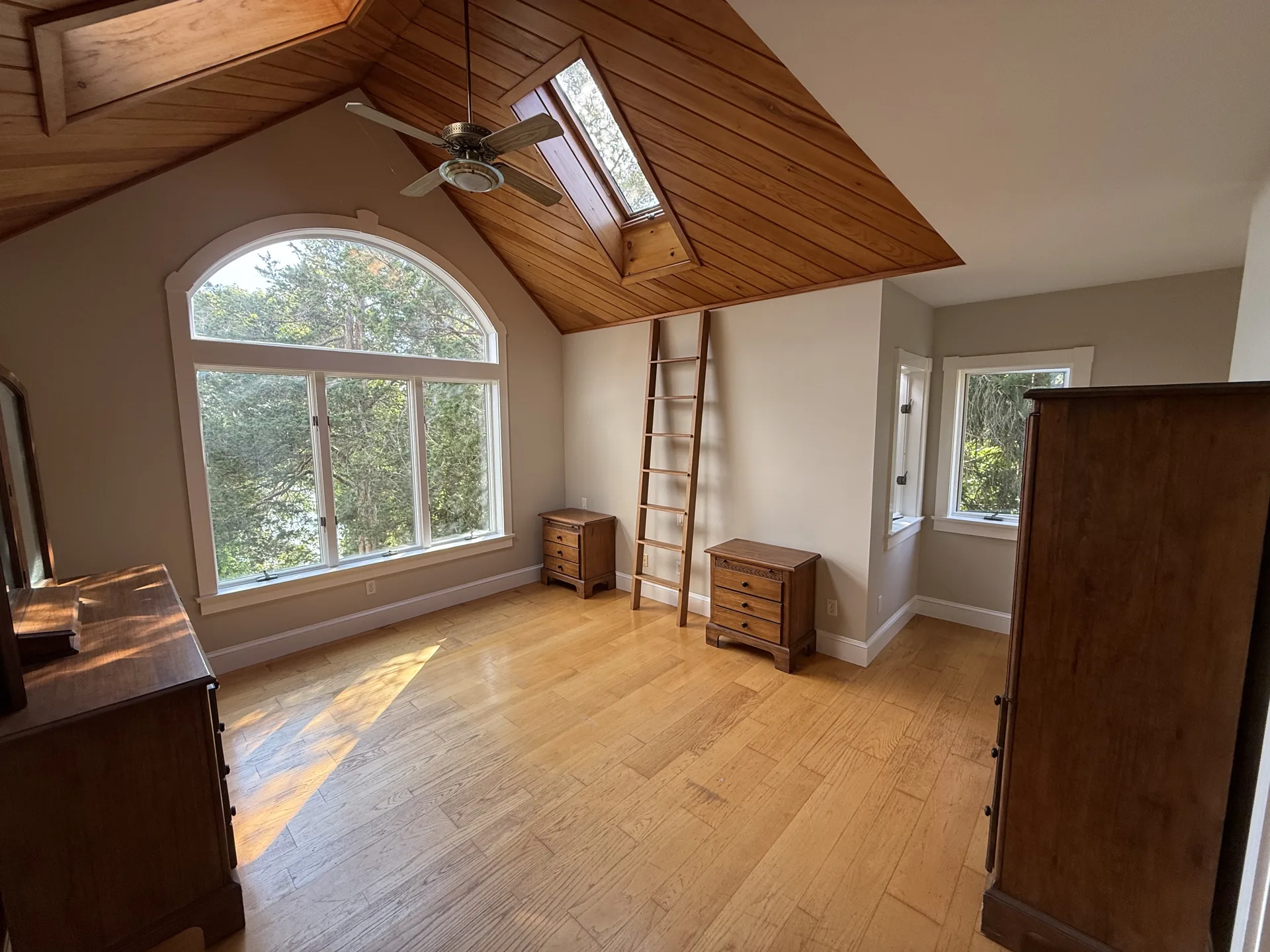 Vaulted wood ceiling bedroom with arched window after interior repaint
