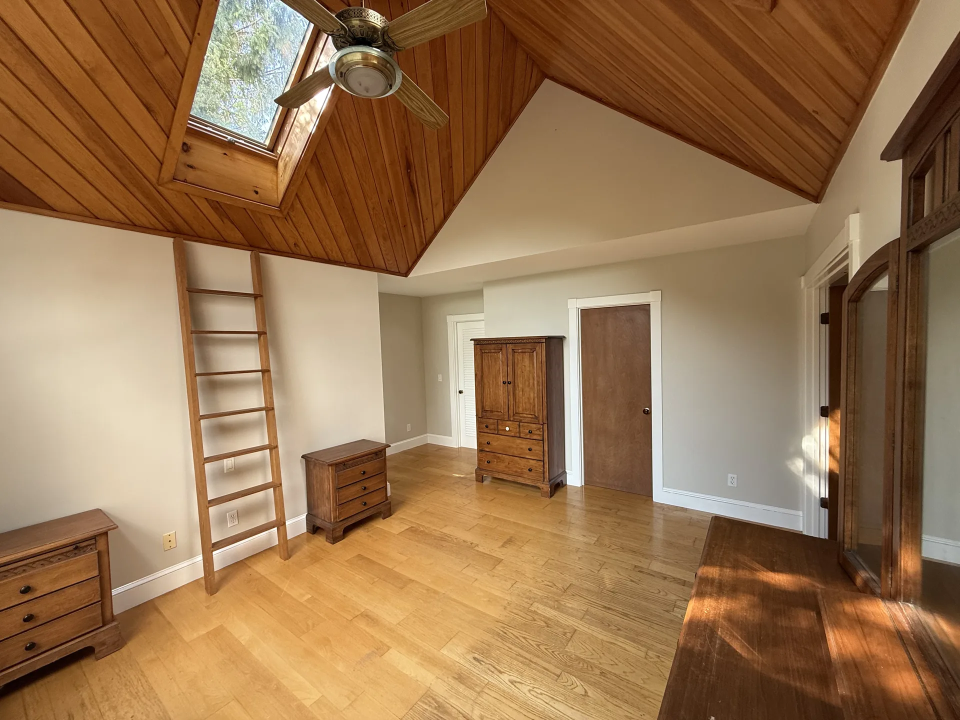 Open bedroom with pine vaulted ceiling, skylight and freshly painted walls