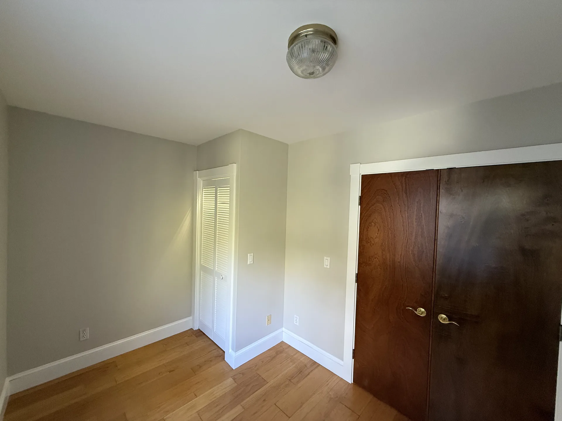 Bedroom corner with smooth wall finish and white baseboards